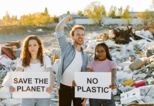 photo shows younger people with poster at a Plastic Dump Site, poster says No Plastic and Save The Planet